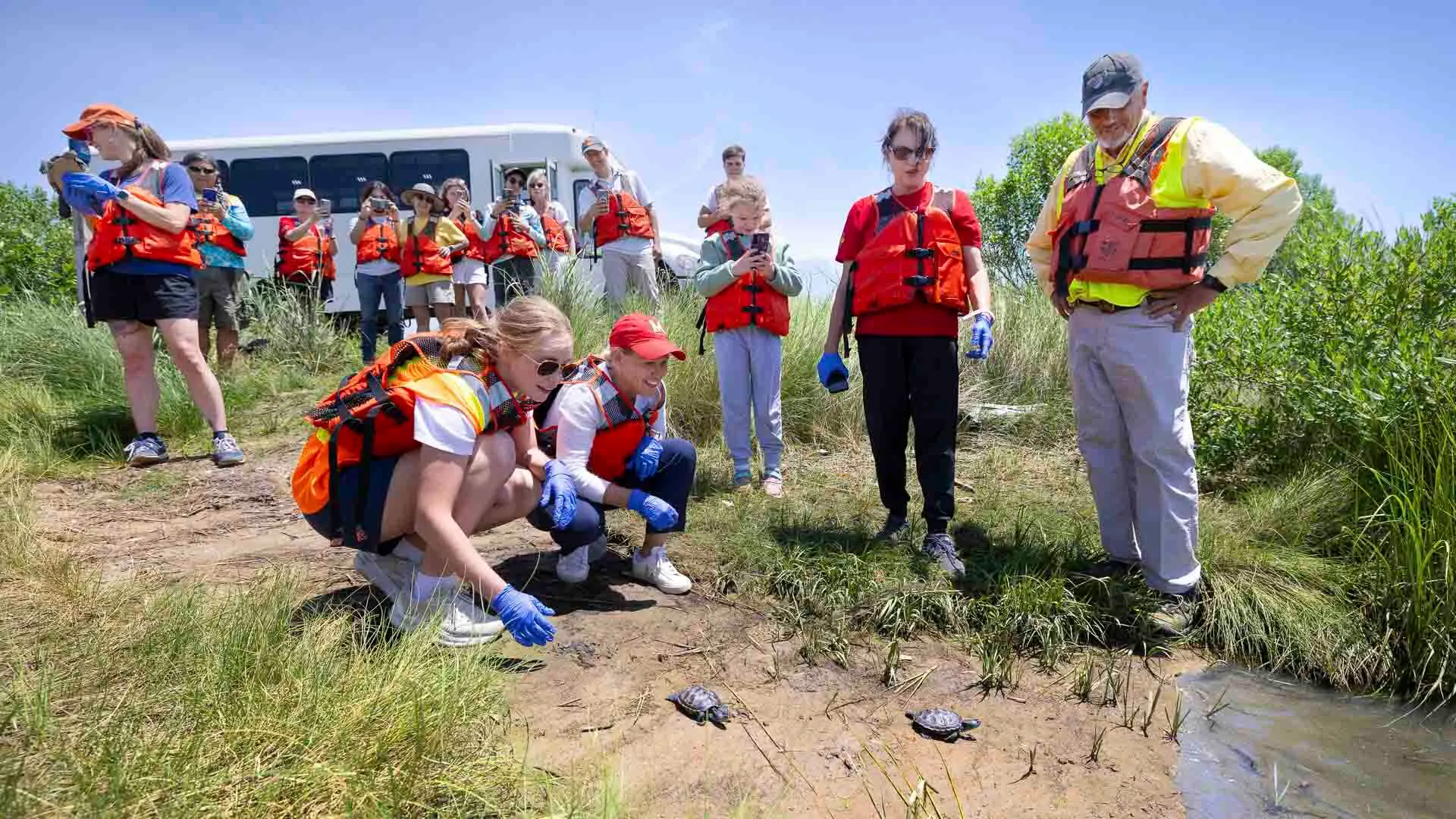 Crouching at the water’s edge on Poplar Island, Provost and Senior Vice President Jennifer King Rice (center) and music education major Lorelai Loyd ’28 release two terrapin hatchlings raised at UMD, Tess and Tudo, into the Chesapeake Bay. Loyd took the Honors College course “Inclusive Conservation: Indigenous Philosophies and Western Science for Biodiversity and Resilience in the Chesapeake and Beyond” in Spring 2026, one of three across UMD that incorporated the terrapins into the curriculum this past school year. (Photos by John T. Consoli)