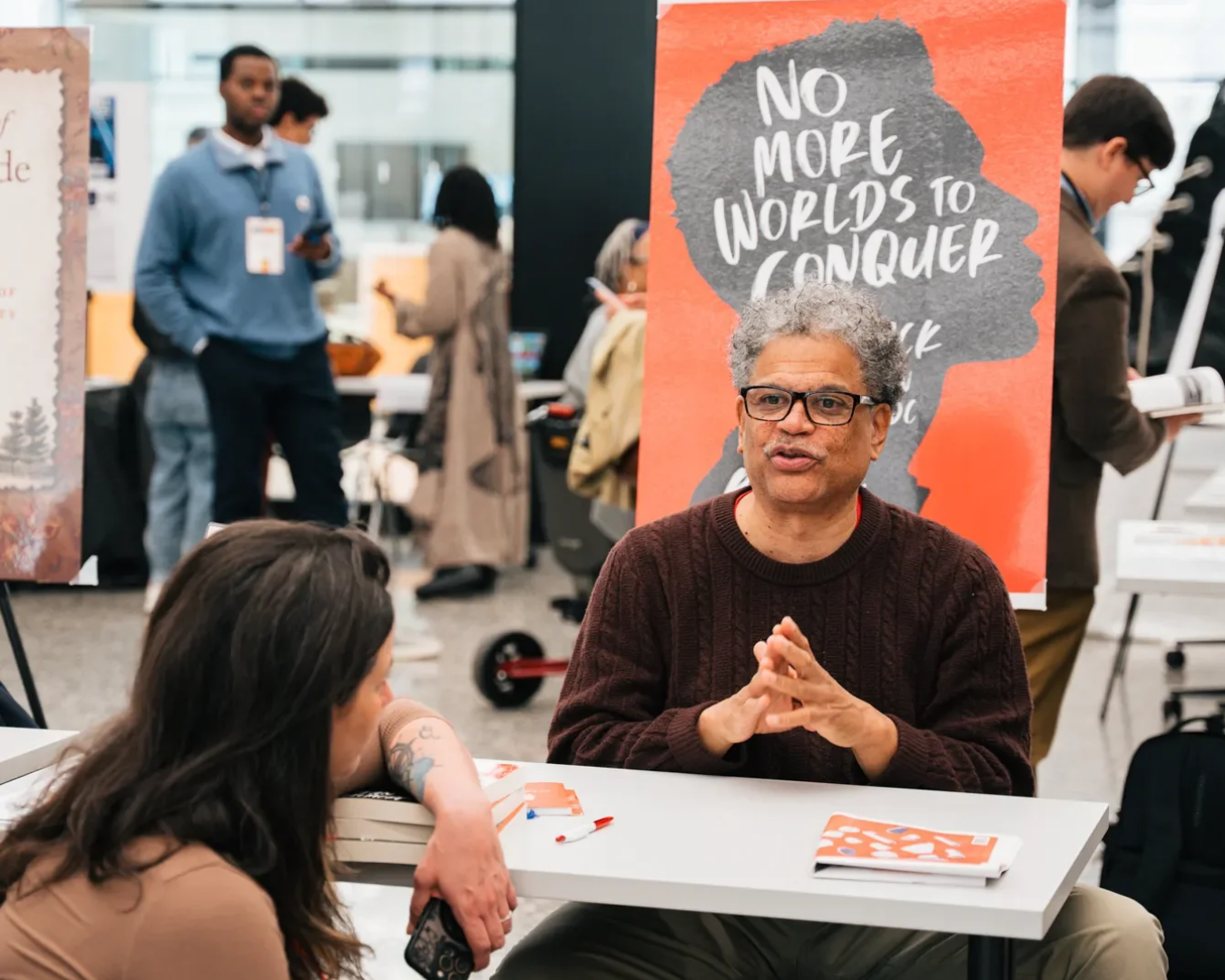Brian Gilmore sits behind a table talking to interested listeners about his book, "No More Worlds to Conquer."